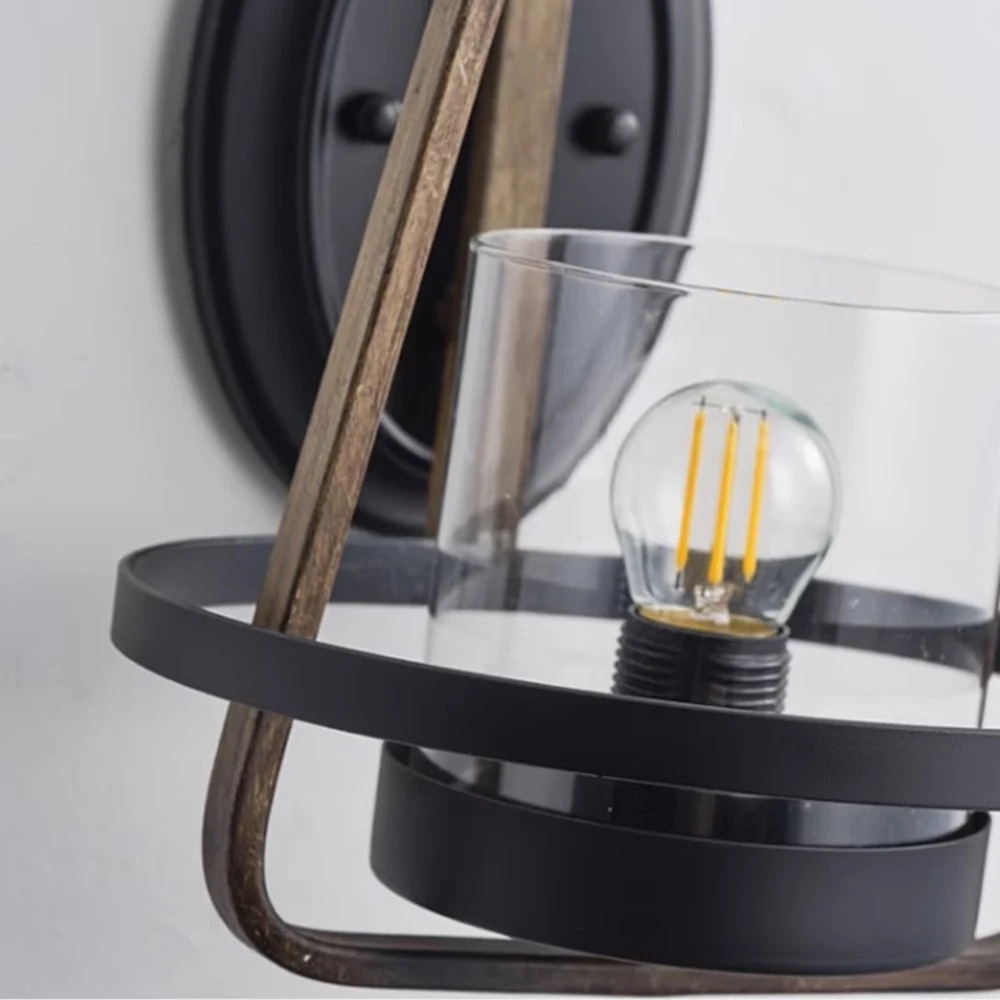 Close view of clear glass shade and black lower ring on rust metal wall sconce