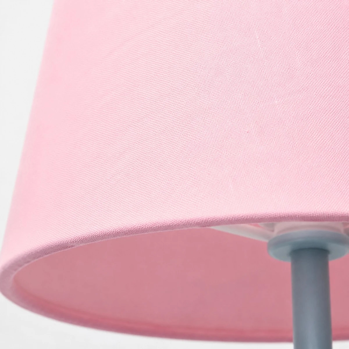 Lower edge of the pink fabric lampshade and metal stem